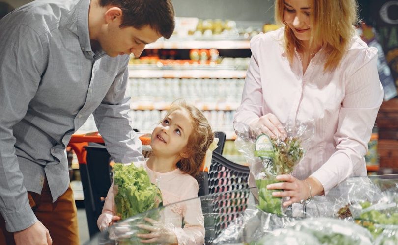 A family enjoys shopping for fresh produce together in a supermarket, smiling and bonding.