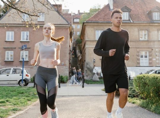 Two young adults jogging on a city path, showcasing an active lifestyle in an urban environment.