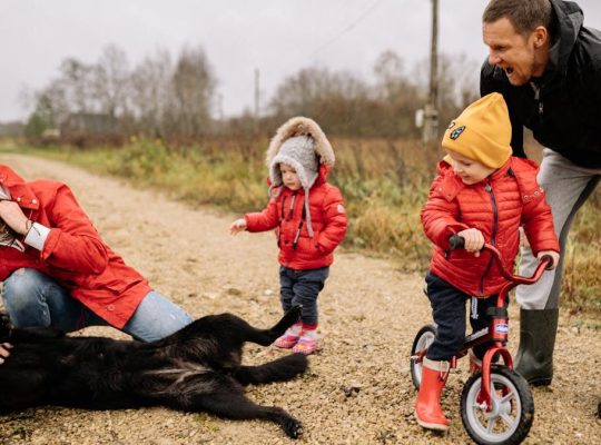 Happy family enjoying quality time outdoors with kids and dog in countryside.
